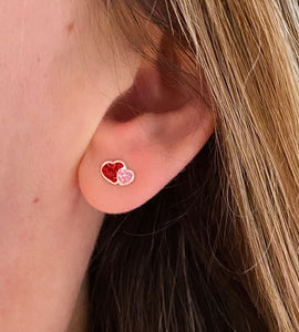 sterling silver double heart studs in red and pink in a model's ear